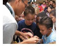 Image of some students looking at a piece of paper that a teacher is holding.
